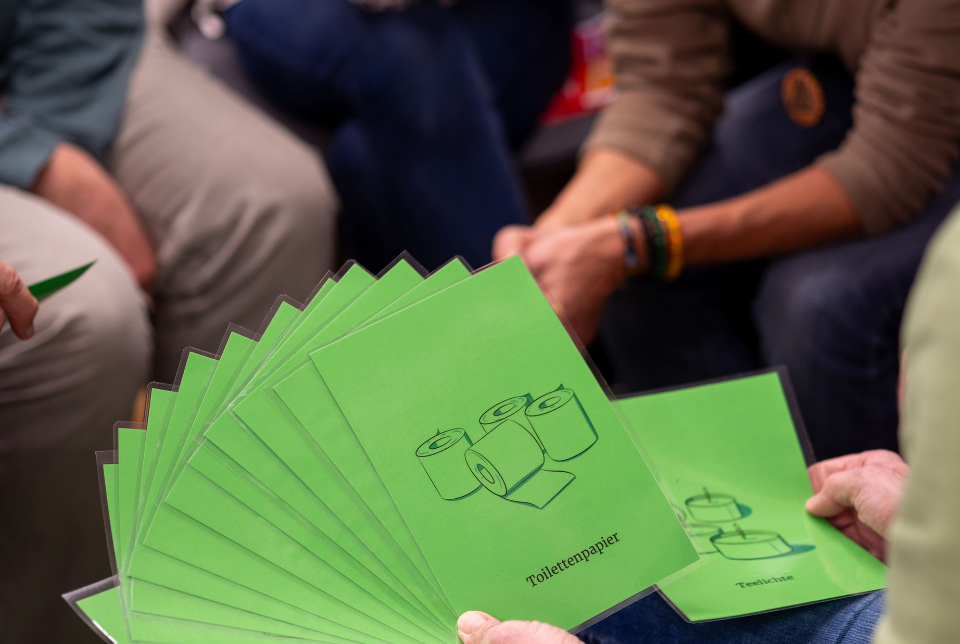 Krisenvorsorge Eine Person hält verschiedene grüne Symbolkarten zur Krisenvorsorge
